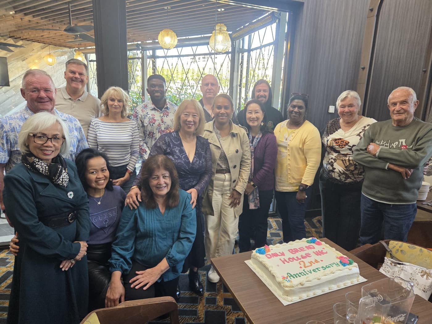 Daily Bread House volunteers and committee gathered around the charity's second anniversary cake.