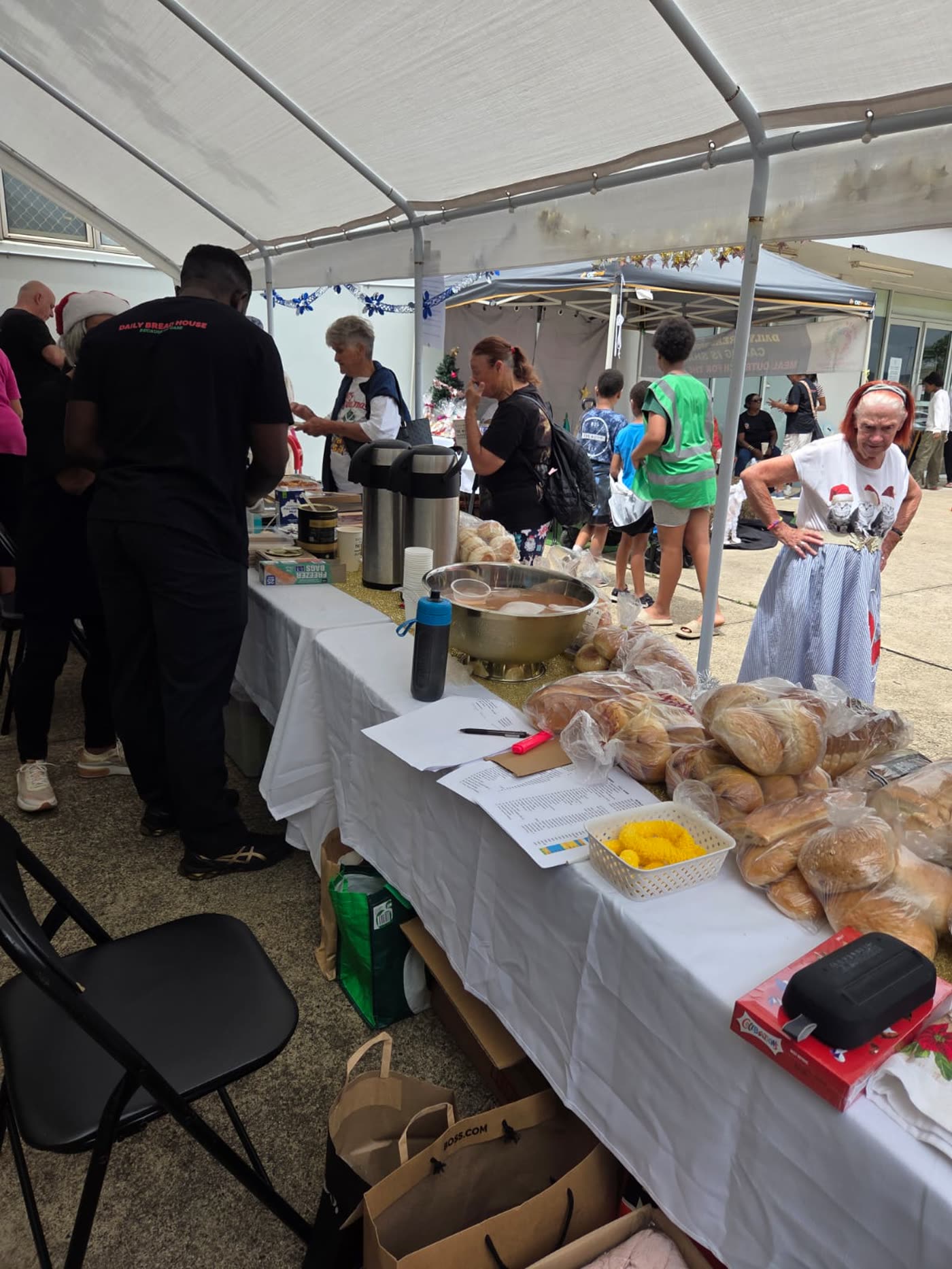 Bread, urns and trestle tables set up at a Daily Bread House community meal.