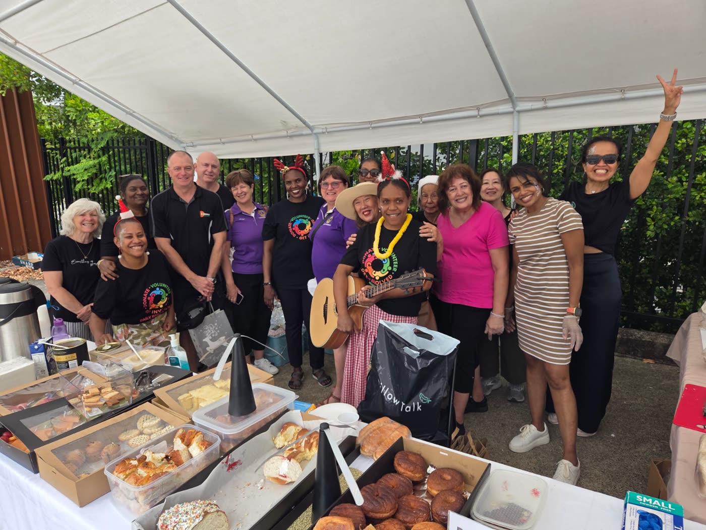 Volunteers gathered behind a long table laid with food at a community meal.
